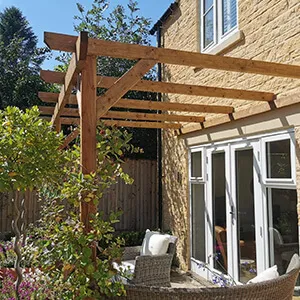 A patio with a table and chairs under a pergolated roof.
