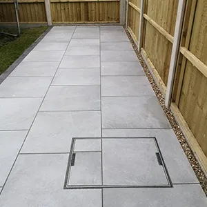 A backyard with a concrete walkway and a wooden fence.